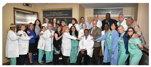 Linwood Haith Jr., M.D., seated at center, and members of the Nathan Speare Regional Burn Treatment Center team gather for a team photo outside of the burn center entrance at Crozer-Chester Medical Center.